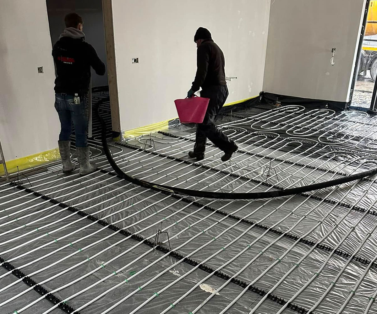 Workers preparing to pour concrete flooring inside a modern house